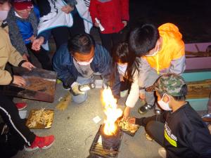 学校支援コーディネーターの方と縄文土器に火を灯す子ども