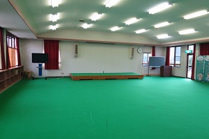 2階にある緑色のカーペットが敷かれた講堂（大広間）簡易ステージやスピーカーが設置されています。