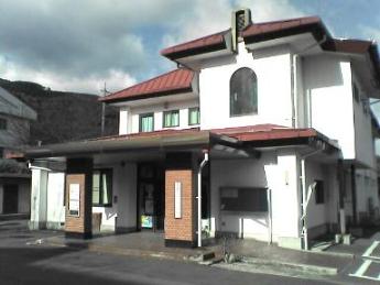 白い外壁と赤い屋根の金沢地区コミュニティセンター正面からの写真。