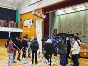 5年生が6年生にむけて作ったくす玉を6年生が全員でわっている様子。