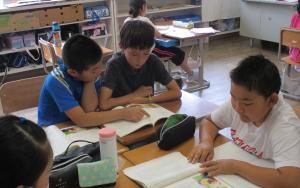 4年生と体験入学に来ている児童が、教室で机を向かい合わせて学習をしている様子。