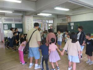 1年生と2年生がロングモント州から来た子たちと手をつないで、「花いちもんめ」をする様子。