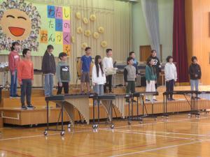 体育館のステージで6年生が合唱をしている様子。