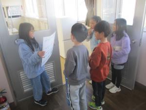 放送委員会の児童が画用紙に書かれた文章を見せながら企画の説明を行っている様子。