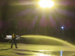 PTA役員の皆さんと支援隊(学校ボランティア)の皆さんが夜の校庭スケートリンクで水まきをしてくださっている様子。