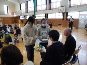 6年生の児童2名がボランティアさんに手紙を渡している様子。